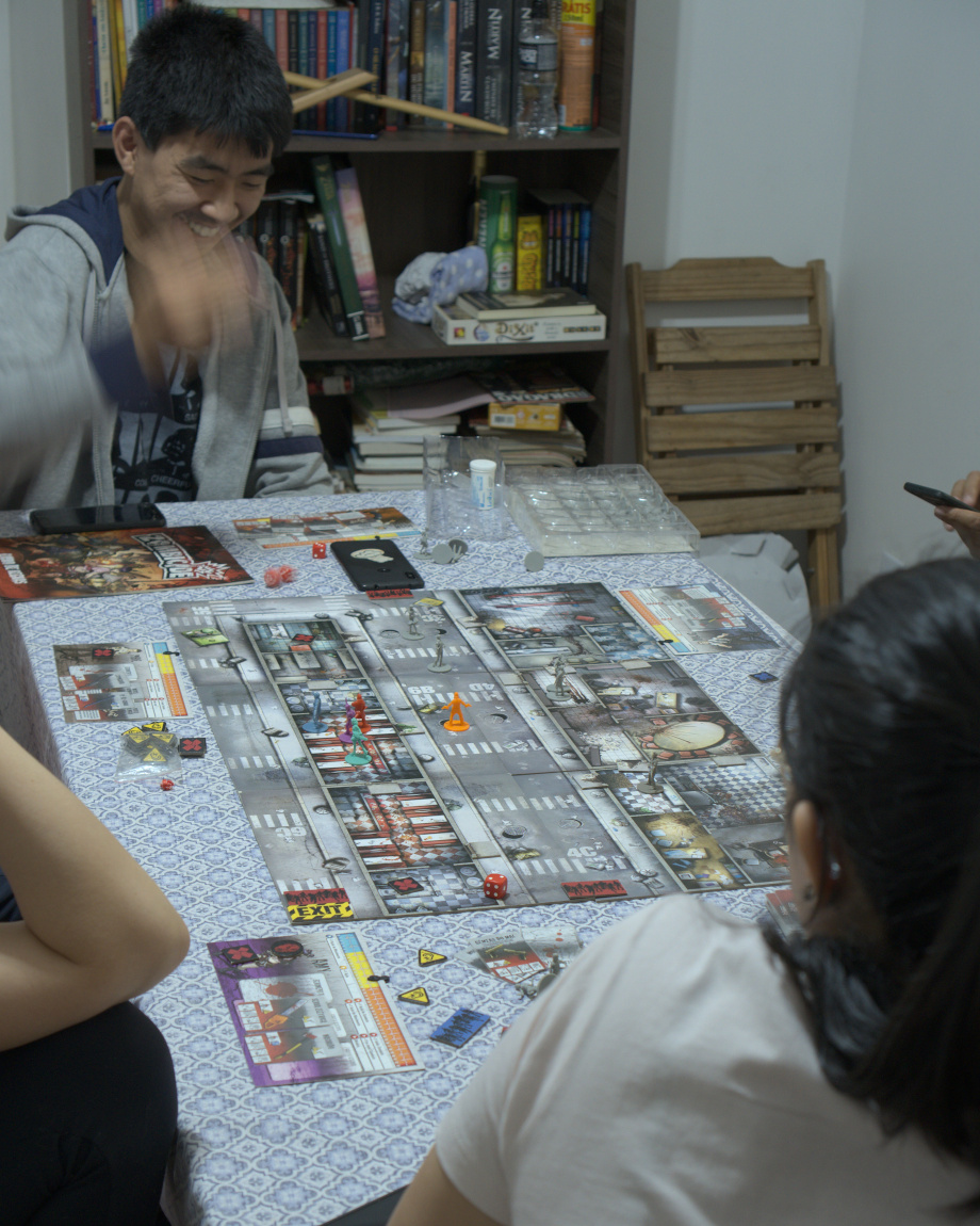 Mitoshi jogando os dados sobre um tabuleiro do jogo zombiecide